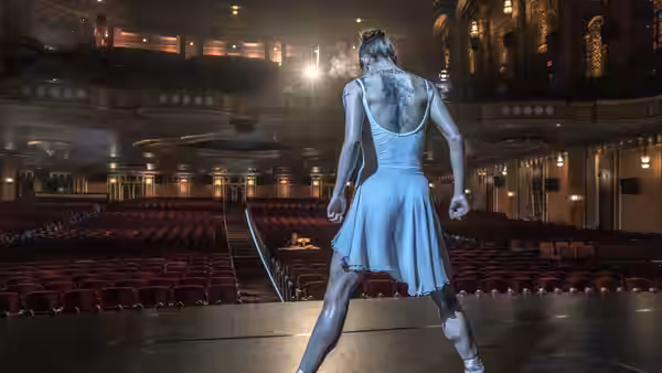 a ballerina standing center stage in an empty ornate theater