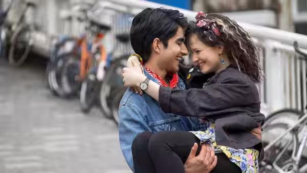 Javed (Viveik Kalra) carries Eliza (Nell Williams) as they embrace on a city street