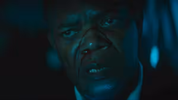 President of the United States (Samuel L. Jackson) grimaces with a bloody nose in dim light