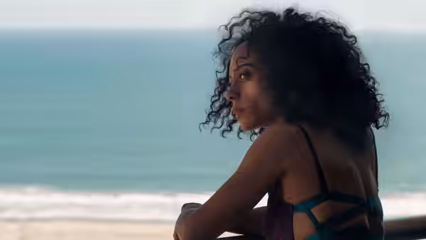 Misty Green (Rosalind Eleazar) sits by the shore, gazing back toward the beach