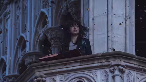A woman leans over an ornate stone balcony as snow falls around her