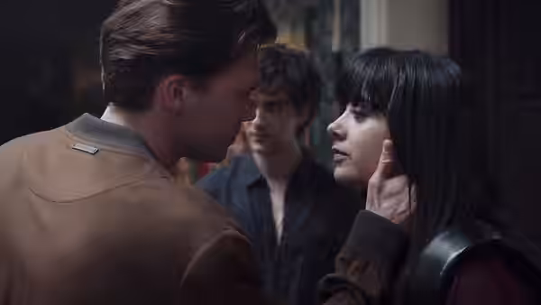 Jude Derry (Irene Balmes) cups a young man's cheek as another man watches