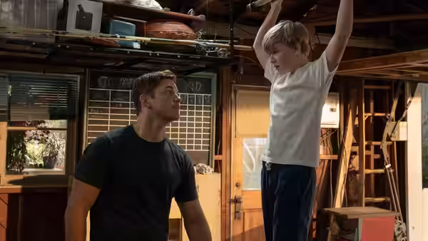 Jake (Chris Pratt) watches a boy hang from an overhead bar in a garage
