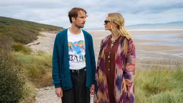 Herb McGwyer (Tom Basden) and Nell Mortimer (Carey Mulligan) stand together on a pebble beach