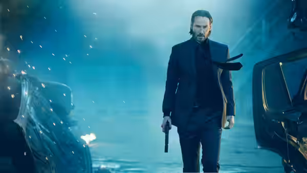 John Wick (Keanu Reeves) walking through wreckage holding a pistol