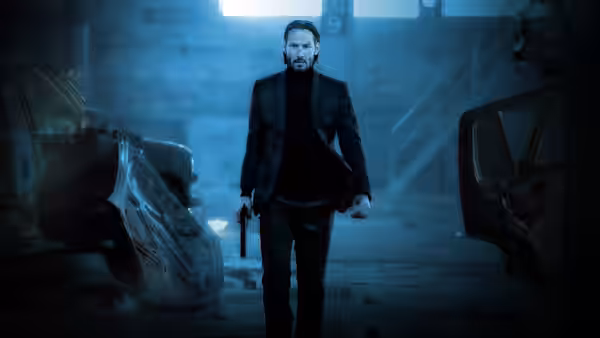 John Wick (Keanu Reeves) walking in a wrecked garage with a gun