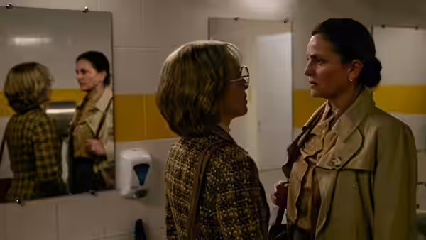 Two women face each other in a restroom