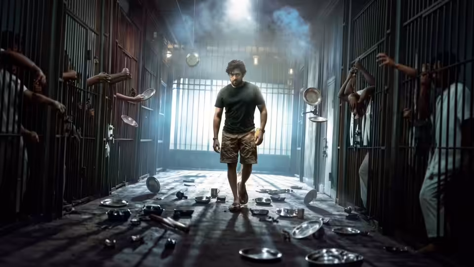 A curly-haired man walks through a prison corridor as inmates reach through cell bars