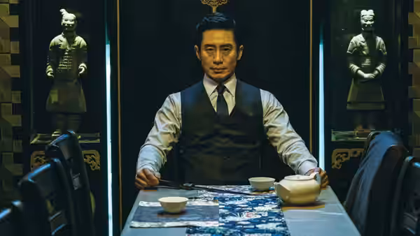 A suited man sits alone at a table between display cases