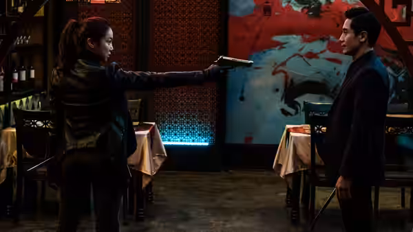 Sook-hee (Kim Ok-vin) points a pistol at a man across a restaurant
