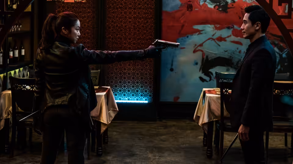Sook-hee (Kim Ok-vin) points a pistol at a man across a restaurant