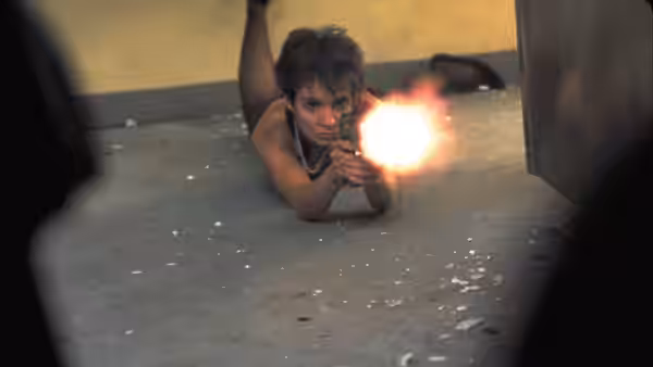Nikita (Anne Parillaud) firing a handgun while lying on the floor