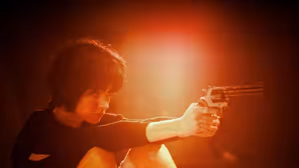 Nikita (Anne Parillaud) aiming a revolver with both hands in red light