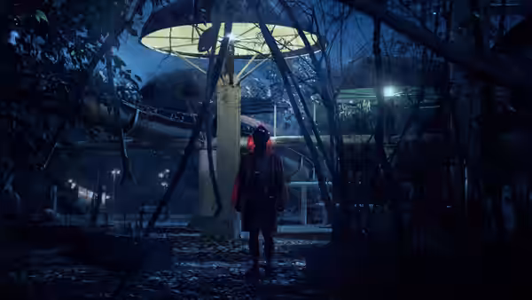 A lone figure in a red jacket stands beneath a lit structure among overgrown trees