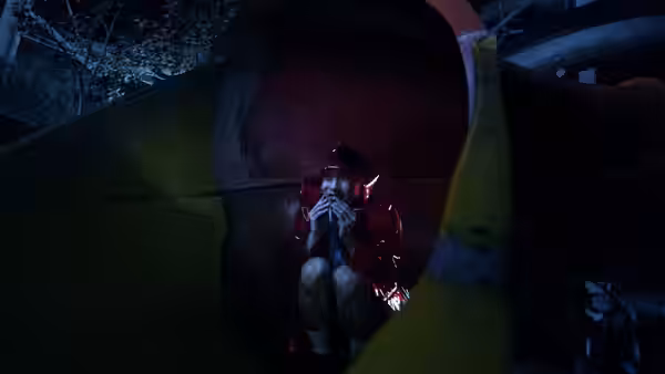 A person in a red jacket crouches inside a large hollow amusement structure