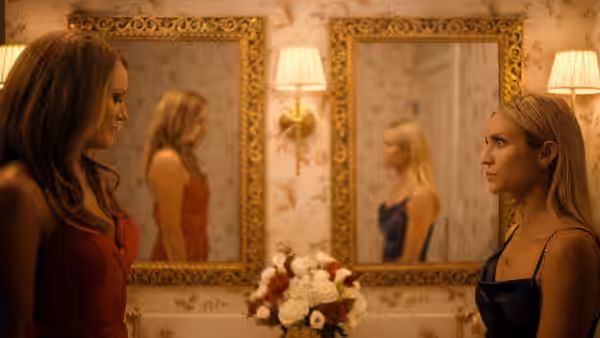 Two women face each other in an ornate room lined with mirrors