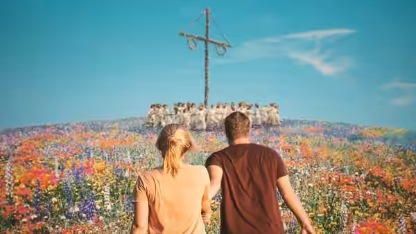 a couple standing in a flower field facing a hilltop gathering