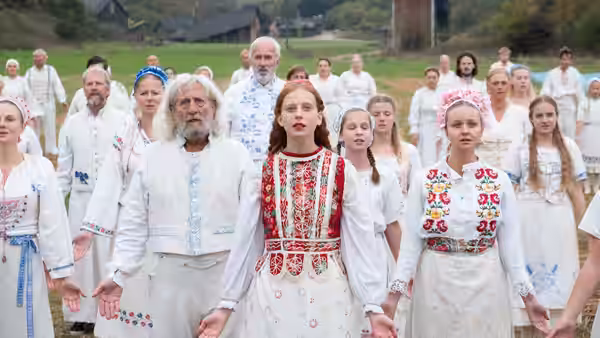 villagers in traditional dress standing together in a grassy field