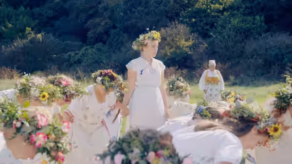 women in flower crowns gathered in a meadow under bright sky