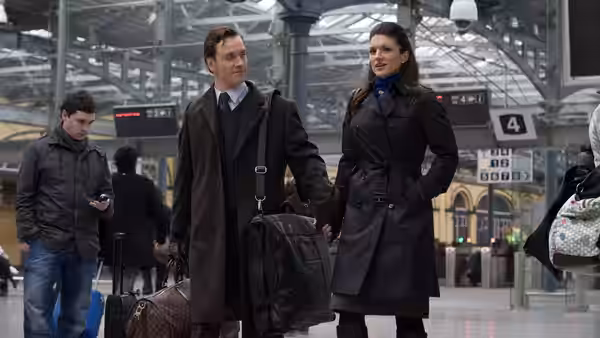 Mallory Kane (Gina Carano) walking through an airport terminal with a man in a coat
