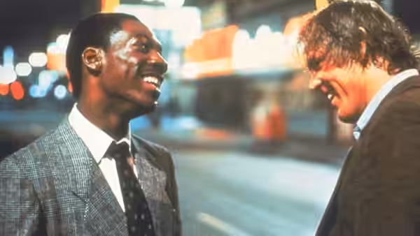 Reggie Hammond (Eddie Murphy) and Jack Cates (Nick Nolte) laugh together on a city street