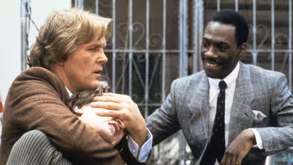 Jack Cates (Nick Nolte) restrains a man as Reggie Hammond (Eddie Murphy) watches
