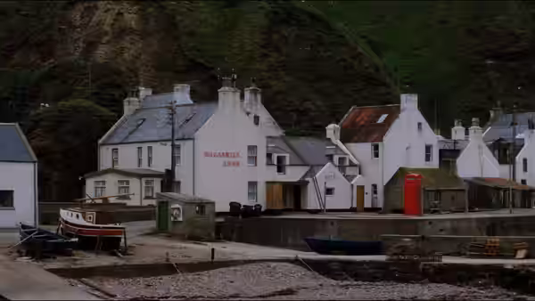 White houses shops and boats along a quiet Scottish coastal harbour