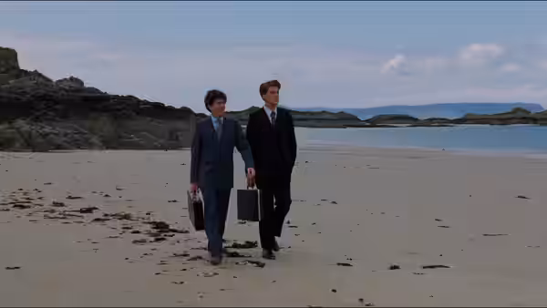 Two suited men with briefcases walking along an empty beach