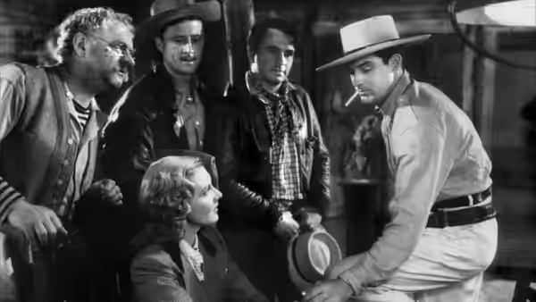 A seated woman looks up at a crouching man as other men watch