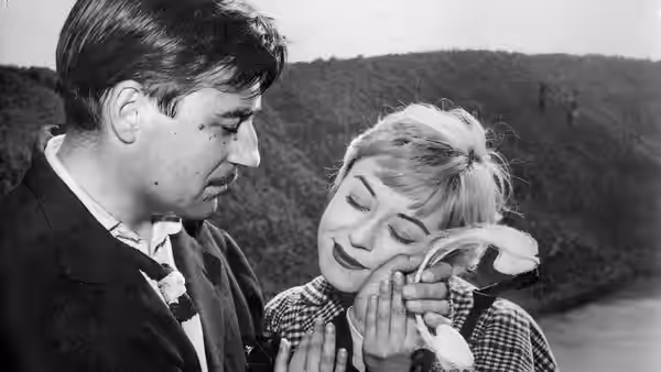 A man watches as a woman presses a handkerchief to her face