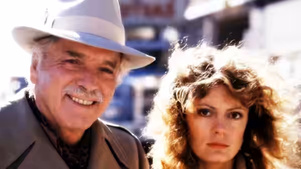 Lou (Burt Lancaster) smiling in a white hat beside Sally (Susan Sarandon) outdoors