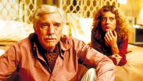 Lou (Burt Lancaster) in bed looking ahead with Sally (Susan Sarandon) beside him