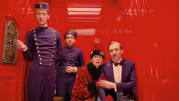 M. Gustave (Ralph Fiennes) and companions inside a bright red elevator
