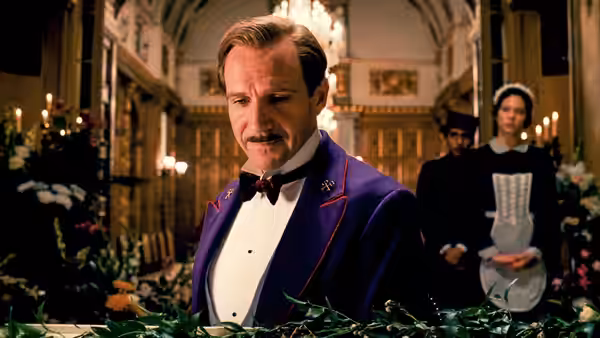 M. Gustave (Ralph Fiennes) with hotel staff in a flower-filled lobby