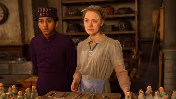 Zero (Tony Revolori) with a woman among trays of colorful pastries