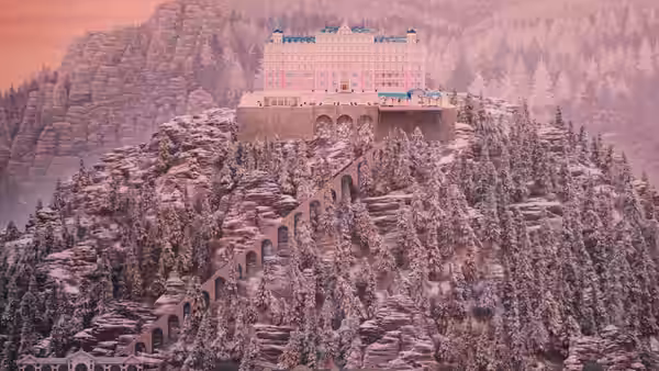 The pink Grand Budapest Hotel atop a snowy mountain at dusk