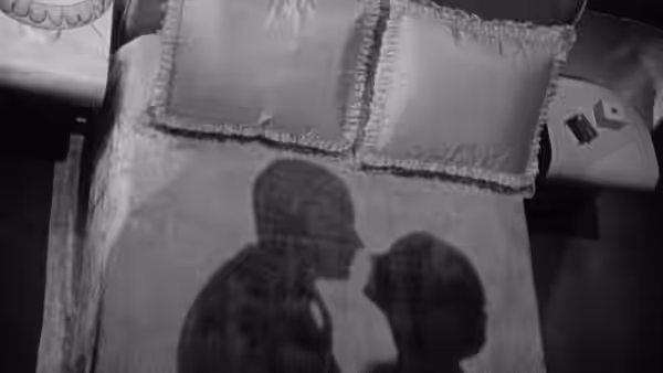 The shadows of a couple fall across a bed and pillows