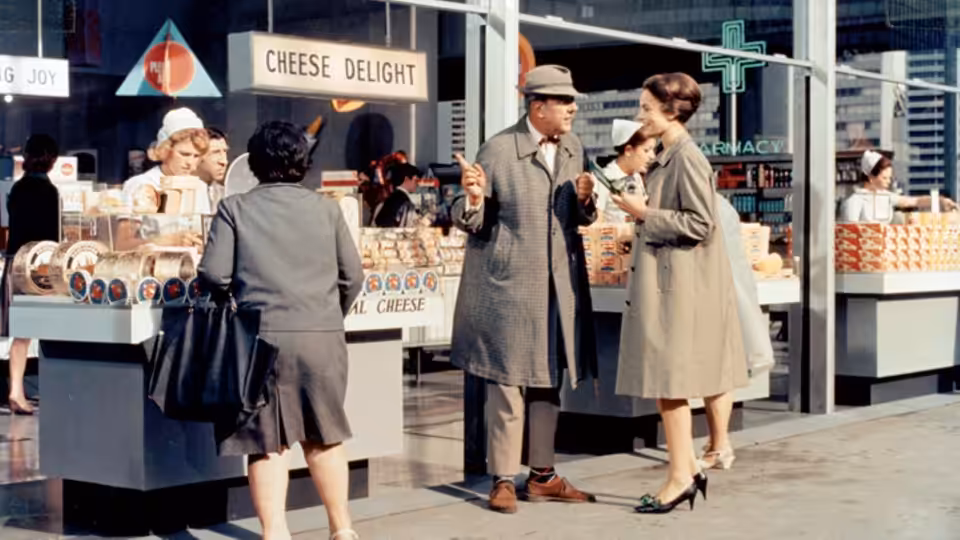 Monsieur Hulot (Jacques Tati) talks with a woman beside a cheese counter