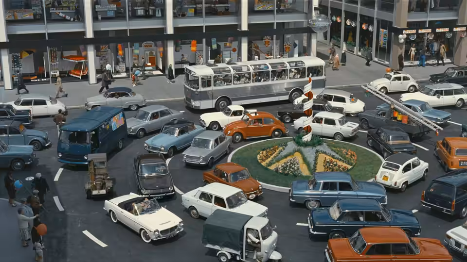 Cars and a bus crowd a city roundabout between tall buildings