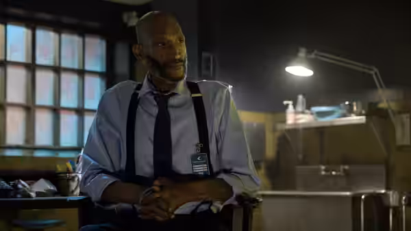 William John Bludworth (Tony Todd) sitting in an office with clasped hands