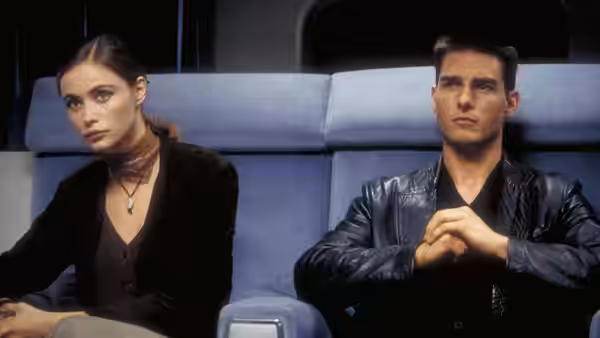 Claire (Emmanuelle Béart) and Ethan Hunt (Tom Cruise) seated side by side in blue chairs