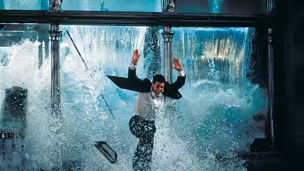 Ethan Hunt (Tom Cruise) bursting through a large window amid a violent water spray