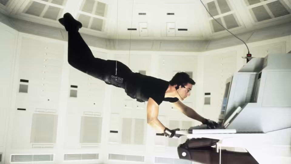 Ethan Hunt (Tom Cruise) suspended from cables accessing a computer terminal in a white room