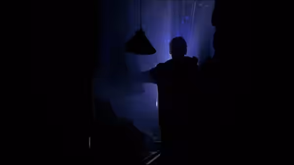Silhouetted figure stands with arms outstretched in a dark blue space