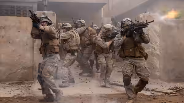 Soldiers advancing and firing weapons in a dusty concrete urban area