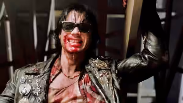 Severen (Bill Paxton), bloodied and grinning, raises an arm
