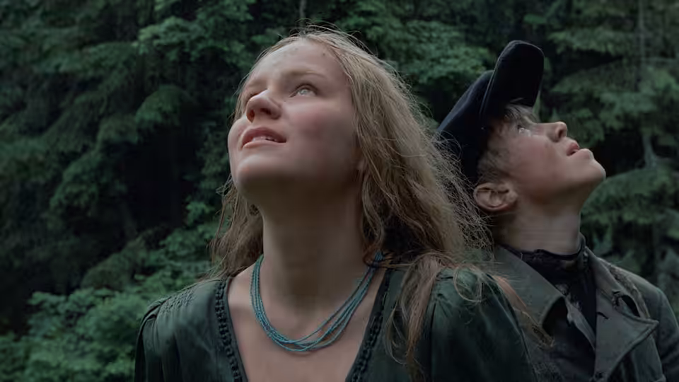 Glasha (Olga Mironova) and Flyora gazing upwards in a dense forest