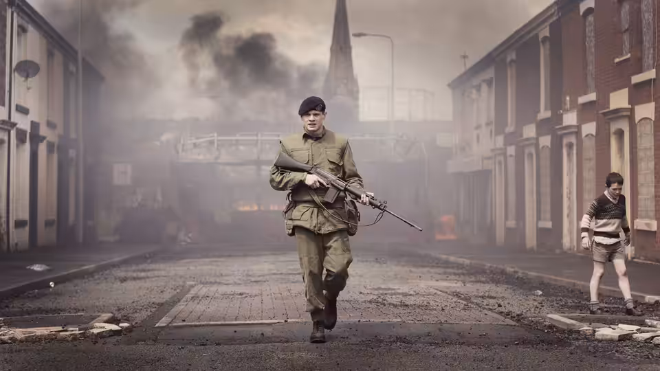 Gary Hook (Jack O'Connell) runs down a smoky street carrying a rifle