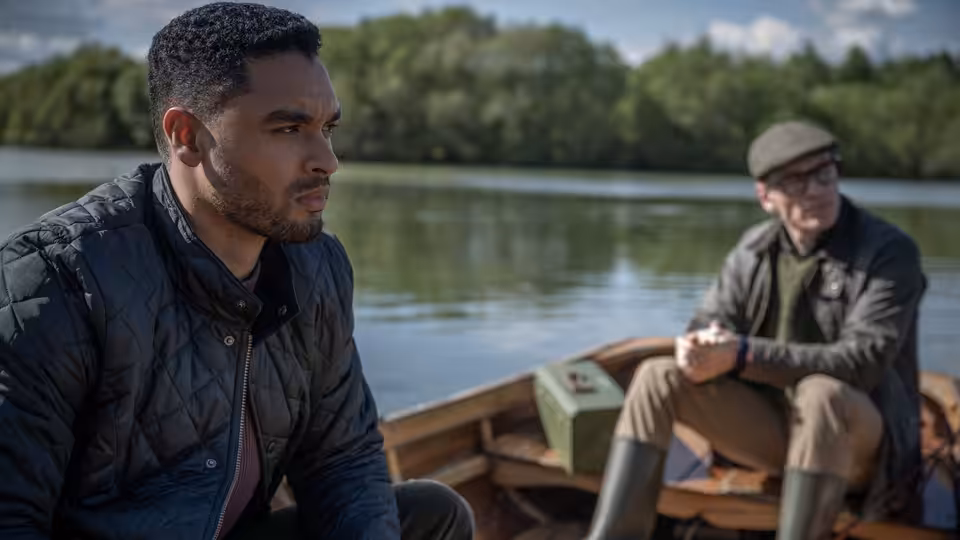 Two men seated in a wooden boat on a calm lake