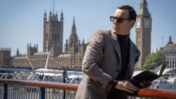 Man in grey suit holding an open book near Big Ben